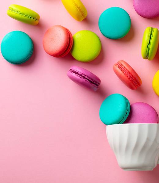 Macaroons dessert and cup of tea on pink background. Flat lay composition. Top view. Copy space.